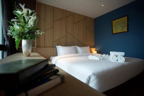 a hotel room with two beds and a vase of flowers at Hotel Fuse Rayong in Rayong