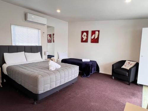 a bedroom with a bed and a chair in it at Morrinsville Motel in Morrinsville