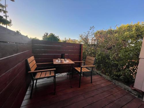 une table et deux chaises sur une terrasse en bois dans l'établissement Studio bas sur Castelginest, à Castelginest