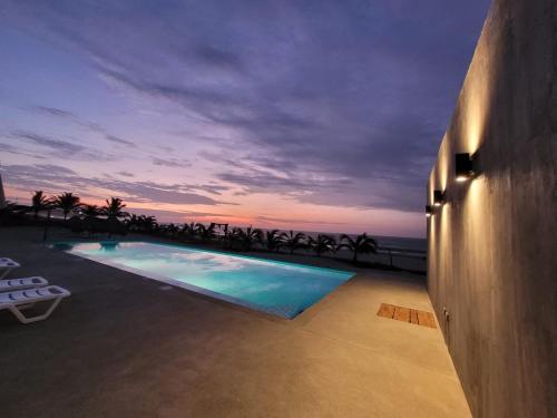 a swimming pool with a view of the ocean at dusk at Las Hamacas in Canoas de Punta Sal