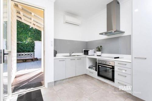 a kitchen with white cabinets and a sliding glass door at Casa de Palmas Noosa in Noosaville
