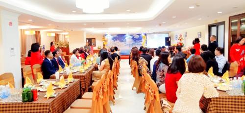 un groupe de personnes assises à des tables dans une pièce dans l'établissement Cầu Giấy Hotel -110 đường Cầu Giấy - by Bay Luxury, à Hanoï