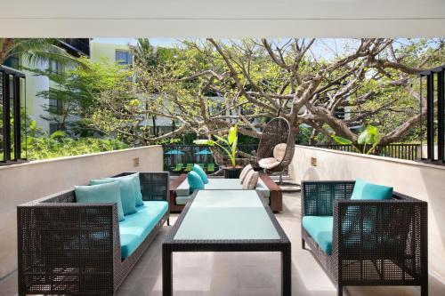 a patio with a table and chairs and a tree at Mercure Bali Legian in Legian