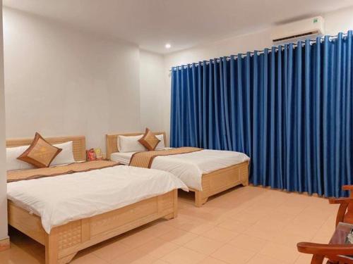 two beds in a room with blue curtains at Hương Quê - 7 Ngõ Ga, Phú Lương, Hà Đông - by Bay Hostel in Hà Ðông