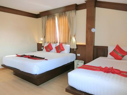 two beds in a hotel room with red pillows at Sira Boutique Chiang Mai in Chiang Mai