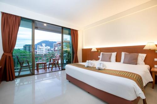 una camera con un grande letto e un balcone di Orchid Garden Hotel a Patong Beach