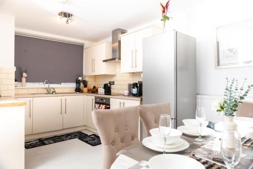 una cocina con armarios blancos y una mesa con sillas. en Spacious House near Kings Cross en Londres