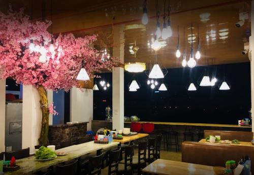 a restaurant with tables and chairs and pink flowers at Thủ Đô Vàng Hotel - QL6 Hà Đông - by Bay Luxury in Hà Ðông