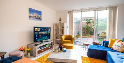 a living room with a blue couch and a tv at Spacious House near Kings Cross in London