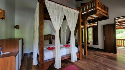 a bedroom with a canopy bed with mosquito nets at Sam's Bungalows And Treks in Bukit Lawang