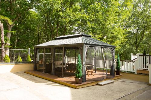 een tuinhuisje met een tafel en stoelen op een patio bij Luxury getaway in vibrant woods. in Bushkill