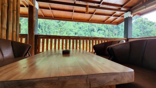 a wooden table and chairs in a cabin with a large window at Sam's Bungalows And Treks in Bukit Lawang