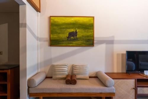 a couch in a living room with a painting on the wall at Dinara Ubud in Ubud