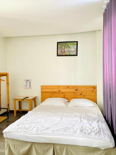 a bedroom with a large white bed with a wooden headboard at Homestay KV in Can Tho