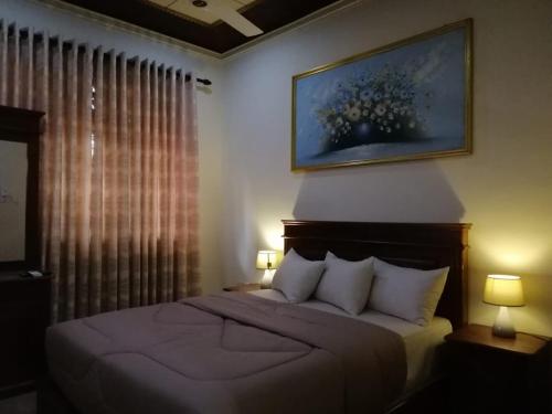 a bedroom with a bed and a painting on the wall at holidays hotel in Dummaladeniya East