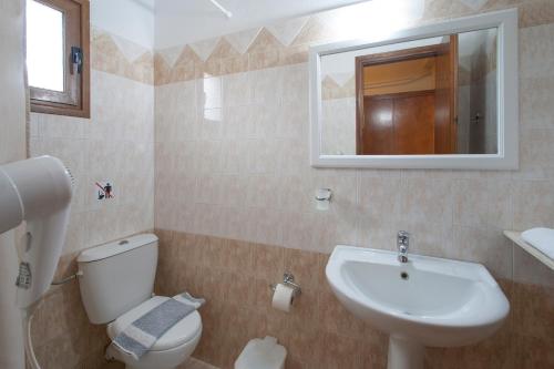 La salle de bains est pourvue d'un lavabo, de toilettes et d'un miroir. dans l'établissement Vontzos Hotel, à Achladies