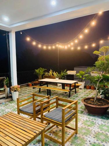 a patio with benches and a table and lights at Homestay KV in Can Tho
