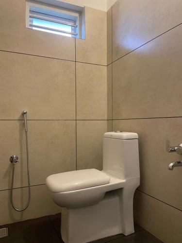 a bathroom with a white toilet and a window at Royal residency in Tindummal