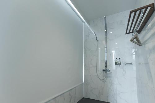 a bathroom with a shower with white marble walls at Sunshine Palm B&B in Magong