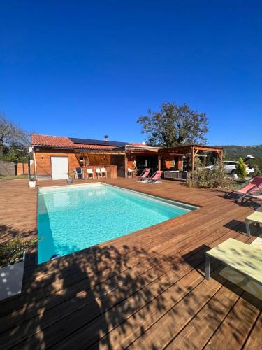 una piscina en una terraza de madera junto a una casa en Maison en bois , plein pieds,piscine privative en Lavelanet