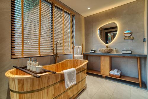 uma casa de banho com uma banheira de madeira e um espelho. em Lady Hill Sapa Resort em Sa Pa