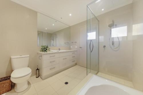 a white bathroom with a toilet and a shower at Arrawong in Merimbula