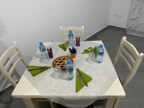 uma mesa branca com cadeiras e garrafas de água em Home Anxhelo em Durrës