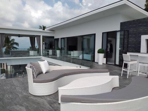 a white couch on a patio with a table at Balcony on the sea in Amphoe Koh Samui