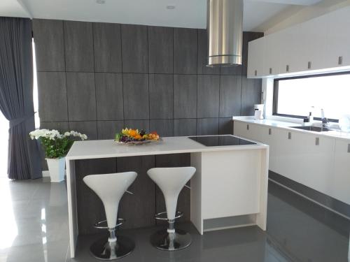 a kitchen with a white island with a sink and stools at Balcony on the sea in Amphoe Koh Samui