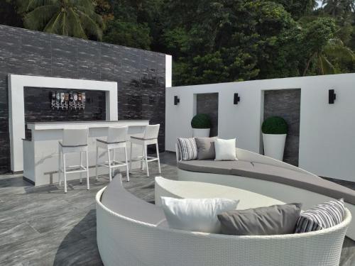 a patio with a couch and chairs and a bar at Balcony on the sea in Amphoe Koh Samui