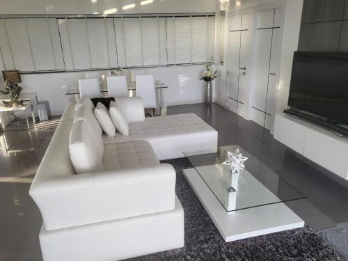 a living room with a white couch and a tv at Balcony on the sea in Amphoe Koh Samui