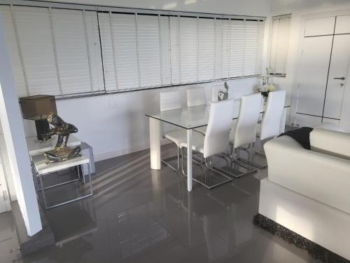 a dining room with a glass table and white chairs at Balcony on the sea in Amphoe Koh Samui