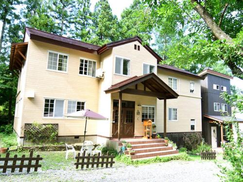 ein großes Haus mit einer Veranda und einer Treppe davor in der Unterkunft Pension Alps Hakuba in Hakuba