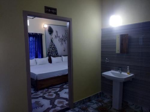 een slaapkamer met een bed, een wastafel en een spiegel bij TITILI PLAZA in Puri