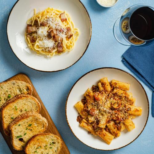 two plates of pasta and bread and a glass of wine at Vivere Hotel and Resorts in Manila