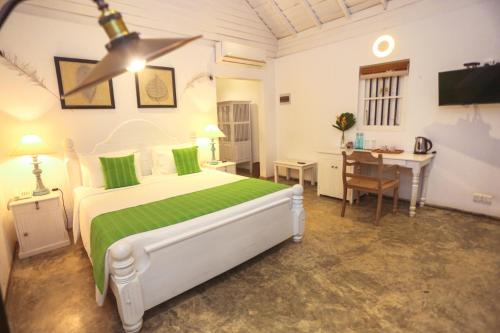 a bedroom with a bed and a table and a desk at Ilukketiya Tea Chalets in Galle
