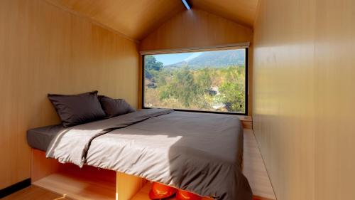 a bed in a small room with a large window at Bobocabin Gunung Rinjani, Lombok in Sembalun Lawang