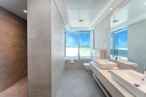 Park Regis by Prince Dubai Islands في دبي: حمام مع حوض ومرآة