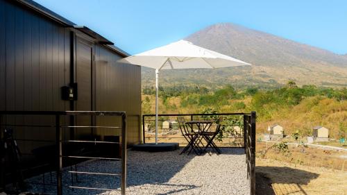 a white umbrella sitting next to a building with a table at Bobocabin Gunung Rinjani, Lombok in Sembalun Lawang