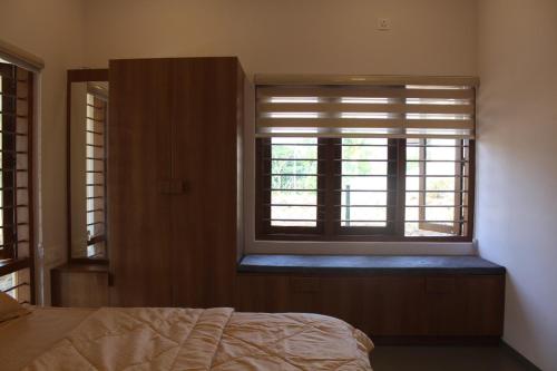 a bedroom with a bed and a window with blinds at Grace villa in Piravam
