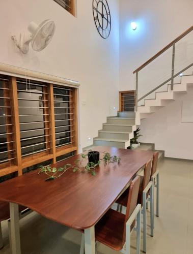 a dining room with a wooden table and stairs at Grace villa in Piravam
