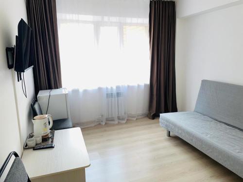 a living room with a couch and a large window at Hotel Palladium in Shchūchīnsk