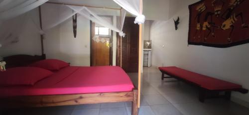 a bedroom with a red bed and a red bench at Résidence Kambana in Nosy Be