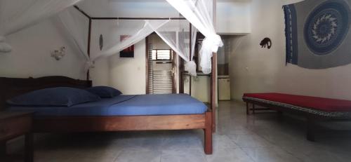 a bedroom with a bed with a blue mattress and a bench at Résidence Kambana in Nosy Be