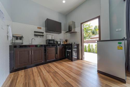 a kitchen with a refrigerator and a wooden floor at N&D Poolvilla in Ao Nang Beach