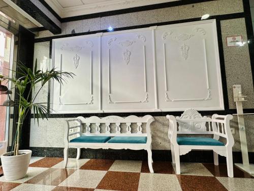 two white benches sitting in front of a wall at Hotel Reyesol in Fuengirola