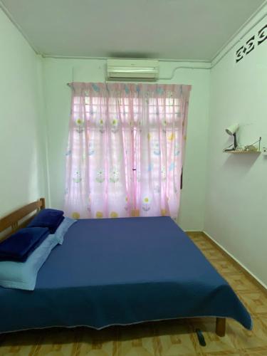 a bedroom with a blue bed and a pink curtain at Homestay Taman Maktab Pengkalan Chepa in Pengkalan Cepa