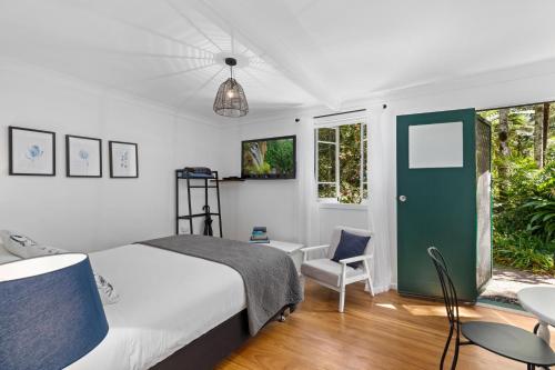 a bedroom with a bed and a chair and a window at Rosella's On Springbrook in Springbrook