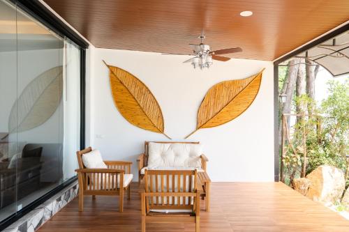 a screened porch with two chairs and a ceiling fan at BeachHouse Pool Villas Krabi in Krabi