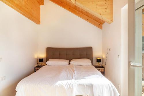 a bedroom with a bed with white sheets and wooden ceilings at Bubbelen aan de piste in Kötschach
